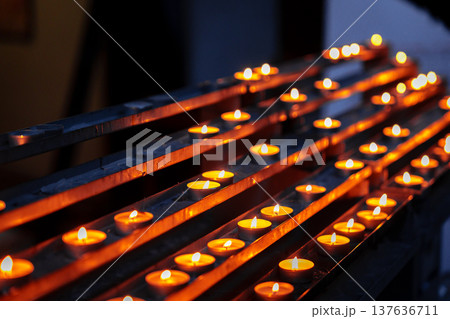 Candles lit in rows during evening ceremony at a local gathering space under dim light Candles lit in rows during evening ceremony at a local gathering space under dim light 137636711