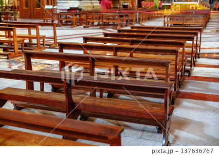Wooden benches arranged in a church interior during a quiet time of day 137636767