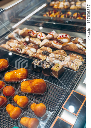 Bakery display shows various types of pastries and sweets in a glass case during the day 137636887