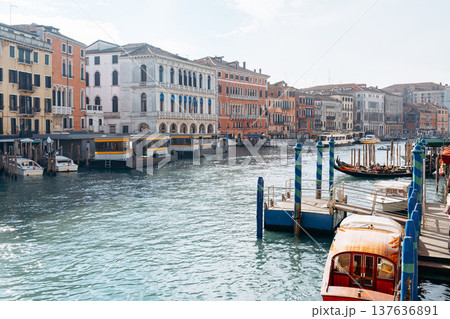 People walk along the canal in Venice while boats float on the water 137636891