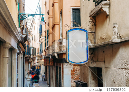 Quiet alley in Venice with a blank sign and a stone lion statue during the day 137636892