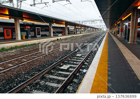 Trains wait at a station as rain clouds gather overhead in a busy urban area 137636899