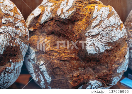 Freshly baked bread loaves displayed on a wooden shelf in a local bakery in the morning Freshly baked bread loaves displayed on a wooden shelf in a local bakery in the morning 137636996