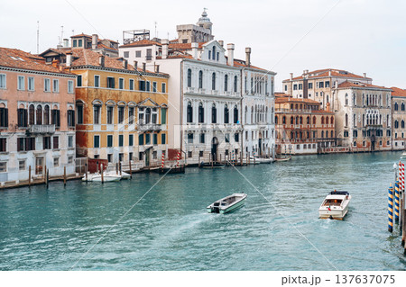 Buildings by the canal in Venice with boats moving in the water on a cloudy day 137637075
