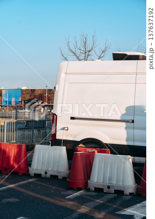 Construction work takes place near a parked van in a busy area during clear weather 137637192