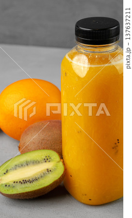 Fresh juice made from fruits displayed on a gray table with a bottle and various fruits Fresh juice made from fruits displayed on a gray table with a bottle and various fruits 137637211