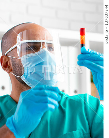 Lab technician examines blood sample in medical facility during daytime work hours Lab technician examines blood sample in medical facility during daytime work hours 137637244
