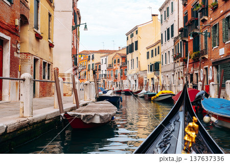 Boats and buildings line a quiet canal in Venice during the daytime with clear skies Boats and buildings line a quiet canal in Venice during the daytime with clear skies 137637336
