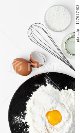 Preparing to bake with flour, eggs, and a whisk on a black plate in a kitchen setting Preparing to bake with flour, eggs, and a whisk on a black plate in a kitchen setting 137637402