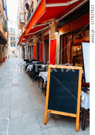 Tables lined up in a narrow street outside restaurants in a famous European city Tables lined up in a narrow street outside restaurants in a famous European city 137637621