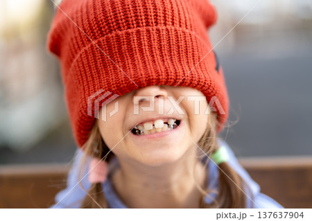 Cheerful girl with red knit cap covering eyes 137637904