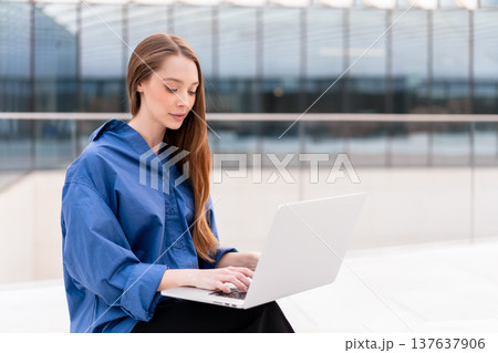 Focused businesswoman working on laptop in front 137637906