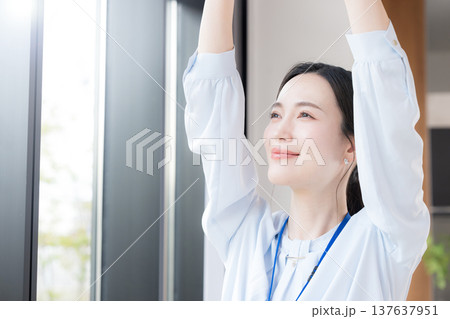 新緑の会社の窓際で伸びやストレッチする休憩するビジネスシーンの女性 スッキリして気分爽快 新緑の会社の窓際で伸びやストレッチする休憩するビジネスシーンの女性 スッキリして気分爽快 137637951