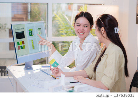 Two asian woman designer using AI artificial intelligence assistant for cosmetic packaging design. 137639033