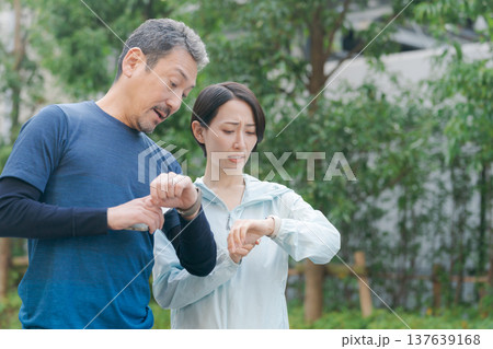 スマートウォッチを見て焦る夫婦 スマートウォッチを見て焦る夫婦 137639168