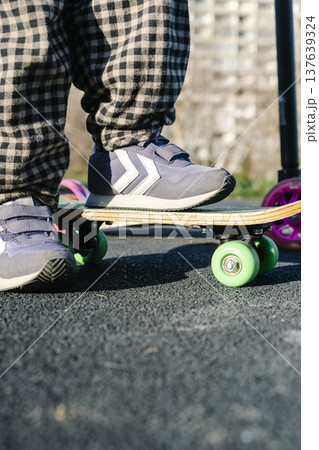 Child's foot on a small green skateboard - outdoor activity. High quality photo 137639324