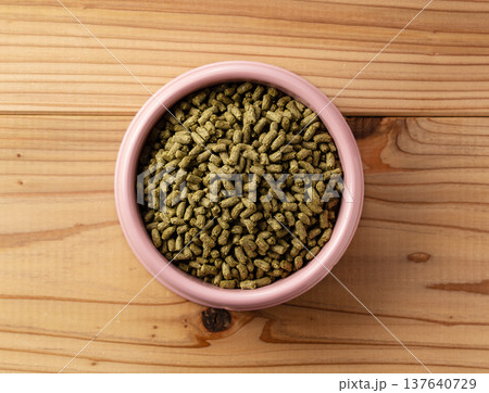 木目のテーブルに置かれたピンクの器とうさぎの餌（ペレット）の真俯瞰 137640729