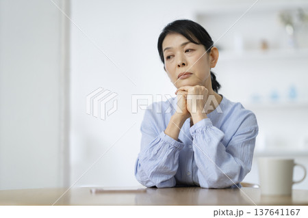 両手に顎を乗せて物思いにふける50代後半の女性 137641167
