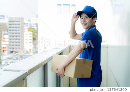 荷物を届ける宅配便の若い男性 荷物を届ける宅配便の若い男性 137641200