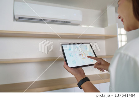 Smart Home Control. Woman using tablet to adjust air conditioning settings. 137641484