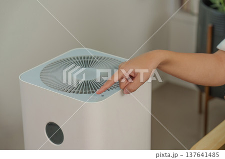 Air Purifier Operation. Person activating air purifier with touch button. 137641485