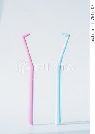 Two single tuft toothbrushes in pink and blue on light background, dental hygiene tools minimal concept 137643407