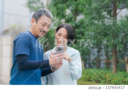 スマホを見るトレーニングウェアの夫婦 137643417