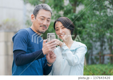 スマホを見るトレーニングウェアの夫婦 スマホを見るトレーニングウェアの夫婦 137643420