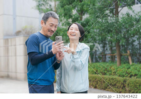 スマホを見るトレーニングウェアの夫婦 137643422