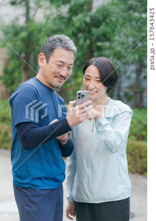スマホを見るトレーニングウェアの夫婦 137643425