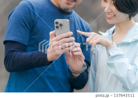 スマホを見るトレーニングウェアの夫婦 137643511