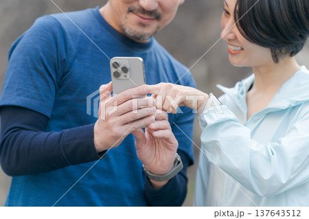 スマホを見るトレーニングウェアの夫婦 137643512