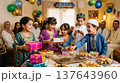 Family at decorated table with gifts and cake celebrating Eid with children dressed in festive clothing. Eid, family, celebration, gifts, cake, children, home, Ramadan. 137643960