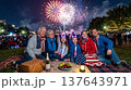 Family sitting on blanket under night sky watching Fourth of July fireworks in park among other picnickers. Fireworks, family, night, park, blanket, summer, picnic, celebration. 137643971