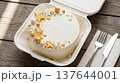 White cake with gold star decorations on plate with fork and knife on wood table top. Cake, gold stars, dessert, celebration, table setting. 137644001
