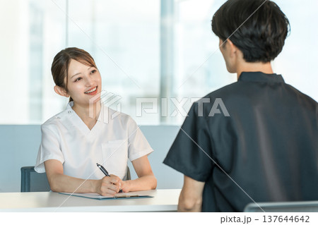 カルテを見ながらカウンセリング,問診,検診,相談をする看護師の女性 カルテを見ながらカウンセリング,問診,検診,相談をする看護師の女性 137644642