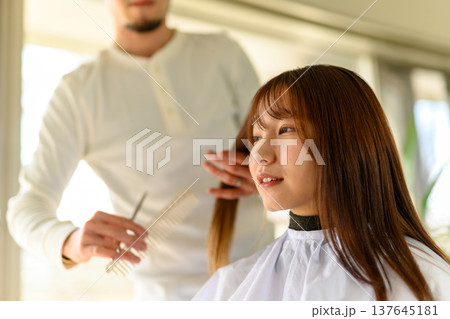 美容師が女性客の髪の長さを確認する 美容師が女性客の髪の長さを確認する 137645181