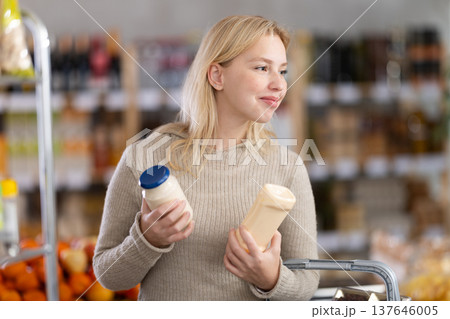 Young woman choosing mayonnaise in grocery store Young woman choosing mayonnaise in grocery store 137646005