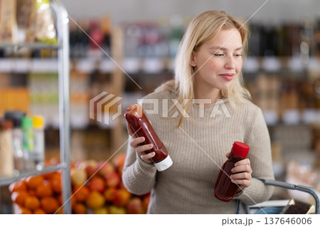 Young woman choosing ketchup in grocery store Young woman choosing ketchup in grocery store 137646006