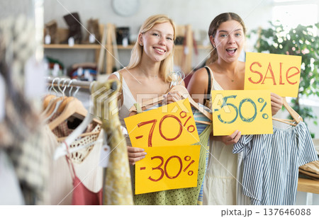 Young women holds yellow poster informing about discounts in store 137646088