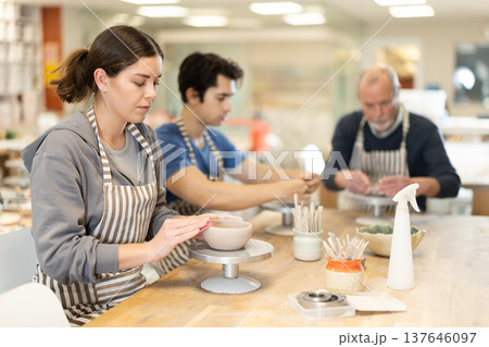 Young woman sculpts ceramic piece in workshop 137646097
