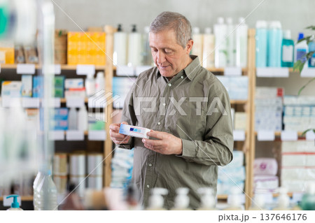 Senior man buys ointment at pharmacy Senior man buys ointment at pharmacy 137646176