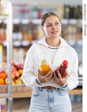 woman chooses between tomato and peach juice woman chooses between tomato and peach juice 137646208