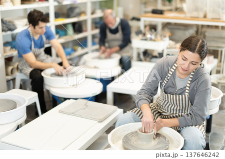 Woman potter works on potter wheel to create clay vase Woman potter works on potter wheel to create clay vase 137646242