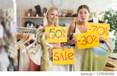 Young women holds yellow poster informing about discounts in store 137646260