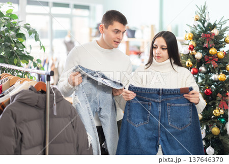Young couple choosing jeans pantaloons in clothing store 137646370