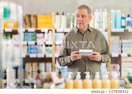Elderly man in a pharmacy chooses pills 137646432
