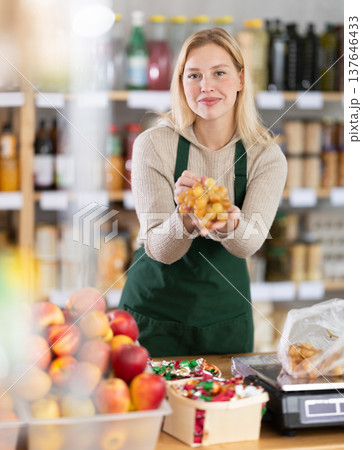 Positive female seller offers to buy delicious grapes 137646433