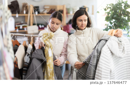Adult woman and teenage girl choose coat or down jacket Adult woman and teenage girl choose coat or down jacket 137646477
