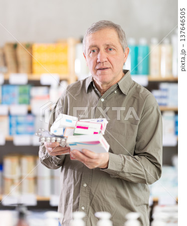 Elderly man comparing medications in pharmacy aisle 137646505